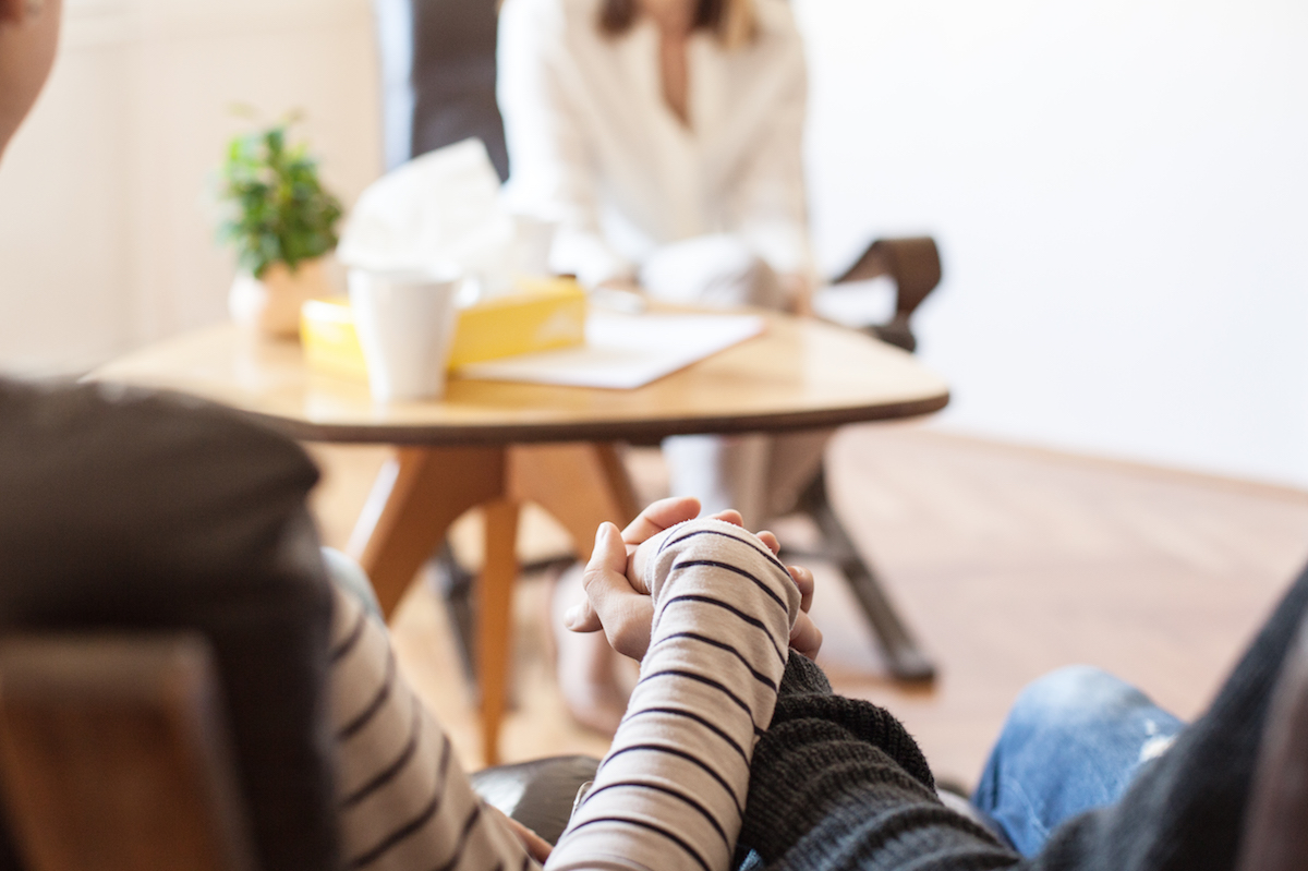 Two people holding hands in therapy session