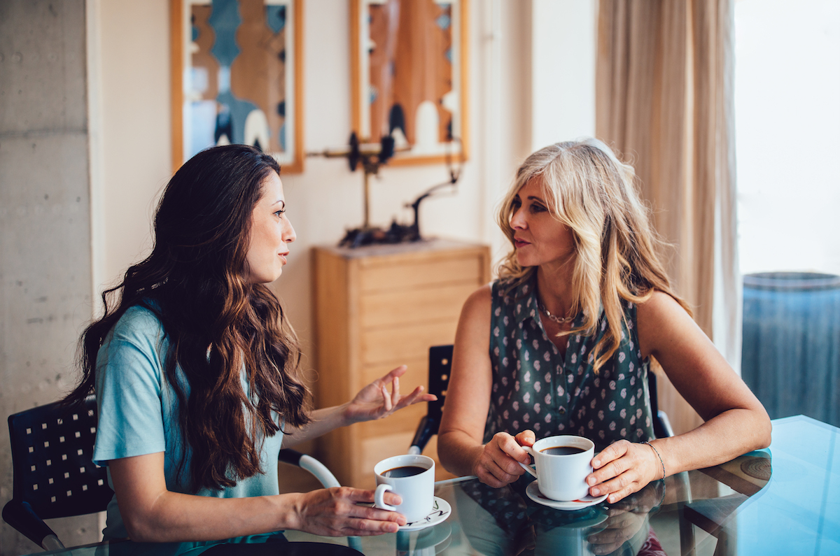 Two women talking and holding coffee