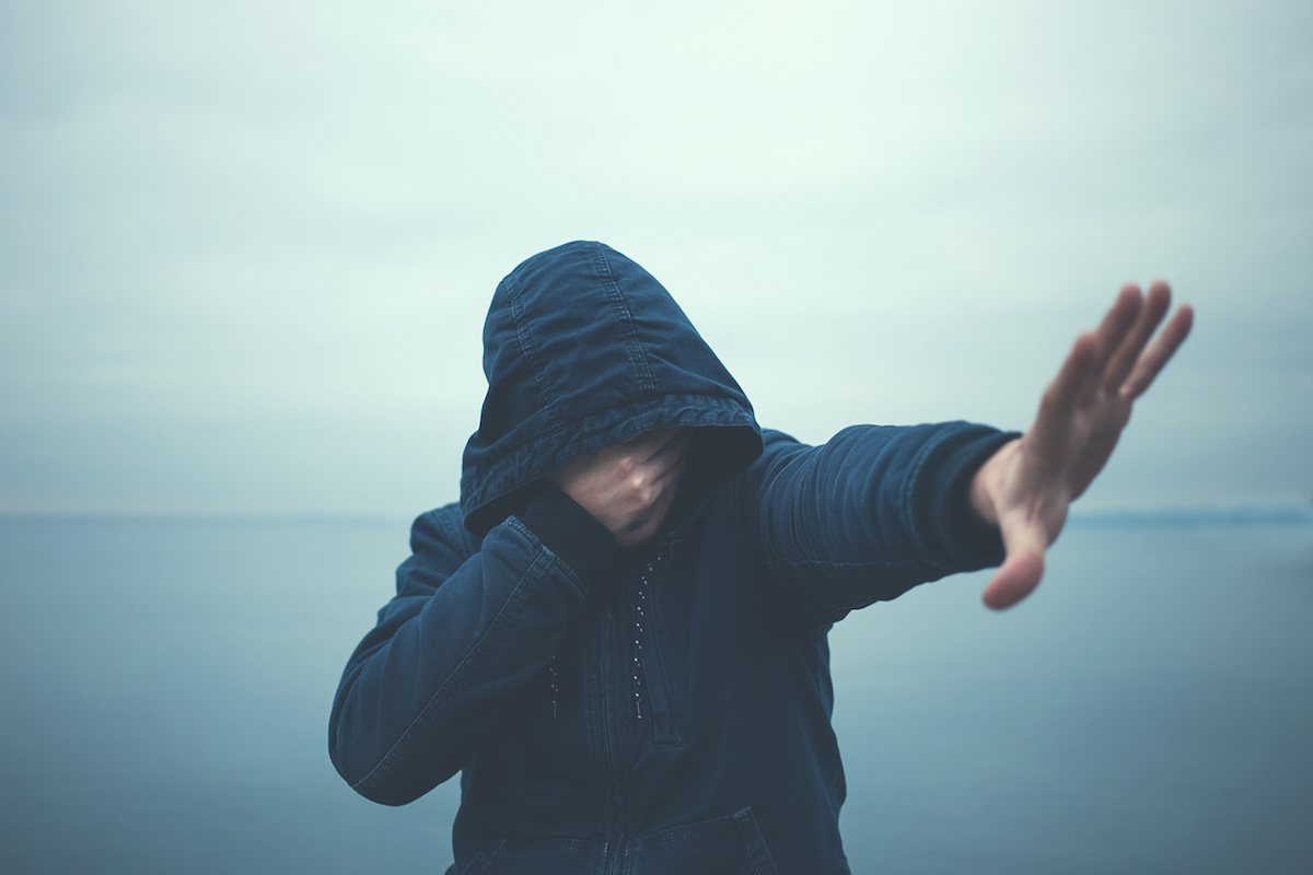 Man in hoodie covering face