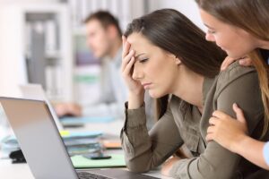 Woman straining to work at laptop, struggling with drug use in the workplace