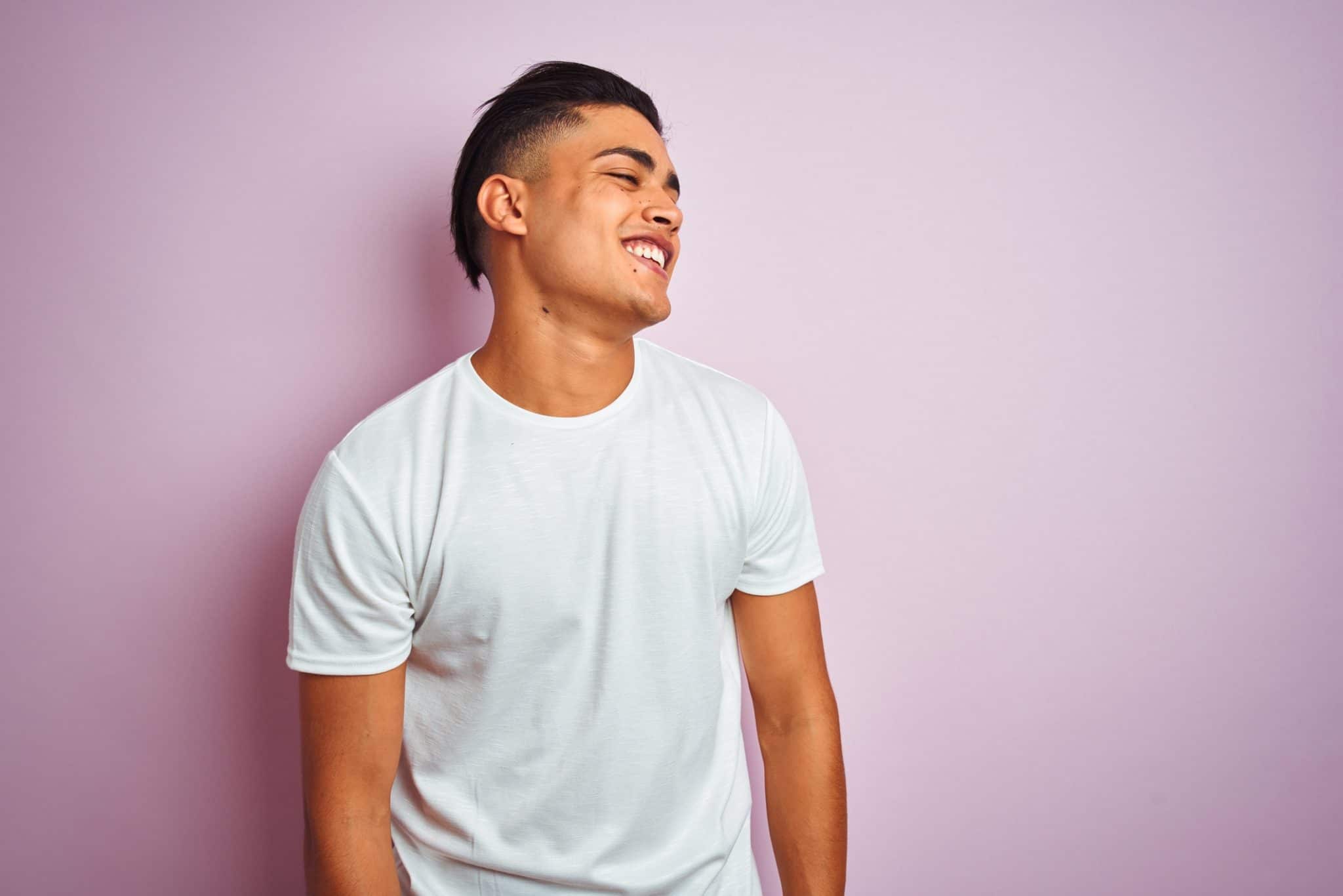 Man standing and smiling against pink wall