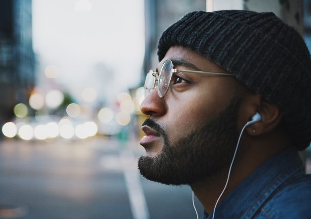 Mann mit Brille hört Musik in der Stadt