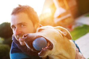 a man playing with his dog and thinking about what to expect in animal-assisted therapy