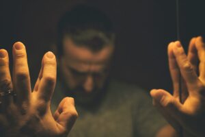 Man puts hands up against mirror, struggling with doing some of the most addictive drugs in the us