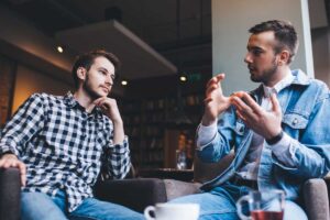 Two people debate over coffee the difference between helping and enabling