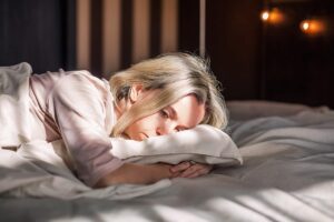 Woman laying on her bed, struggling to get up, despite showing signs of high-functioning anxiety