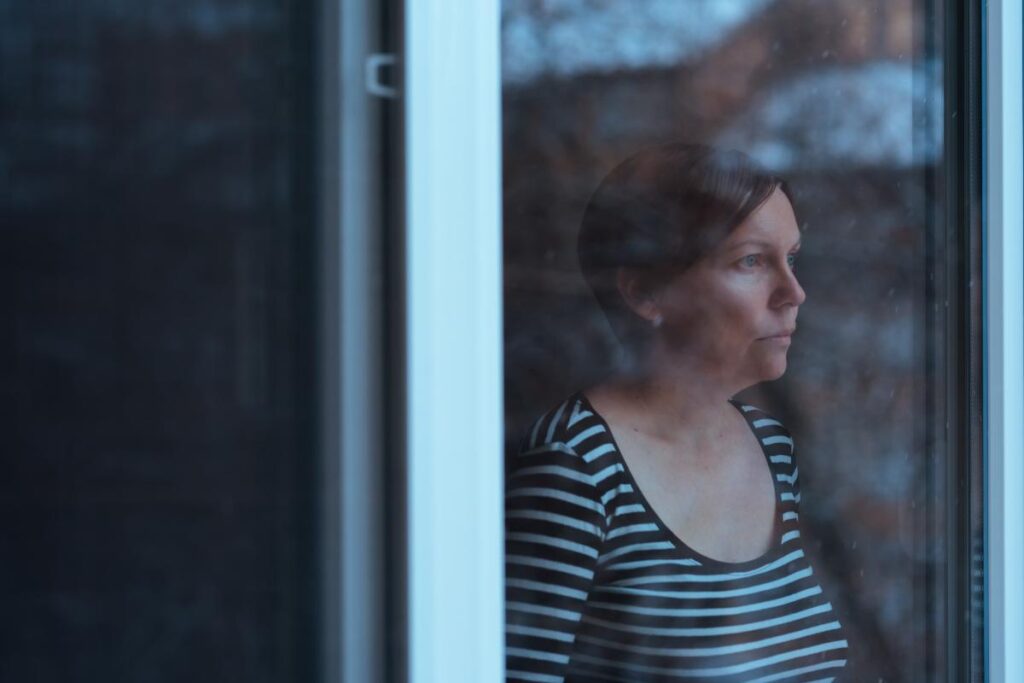 Woman looks out window mournfully as she ponders, "how long does alcohol withdrawal last?"