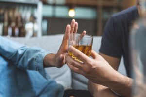 Person puts hand up to glass of alcohol after learning how to stop drinking