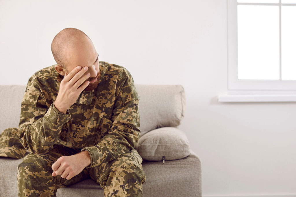 Man sits on couch as he considers veteran addiction treatment program