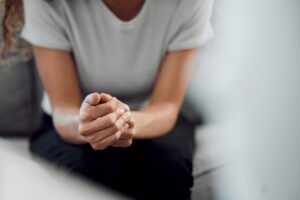 Woman clasps hands together as she wonders how drug rehab works