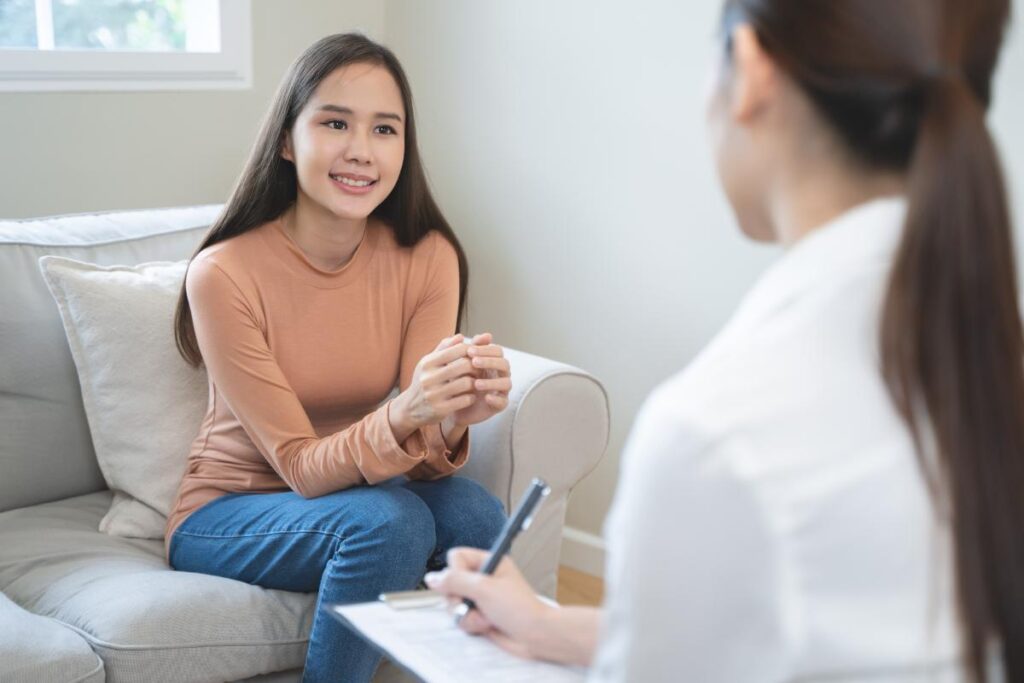 Woman sits on chair and talks to therapist as she learns the benefits of a womens rehab program