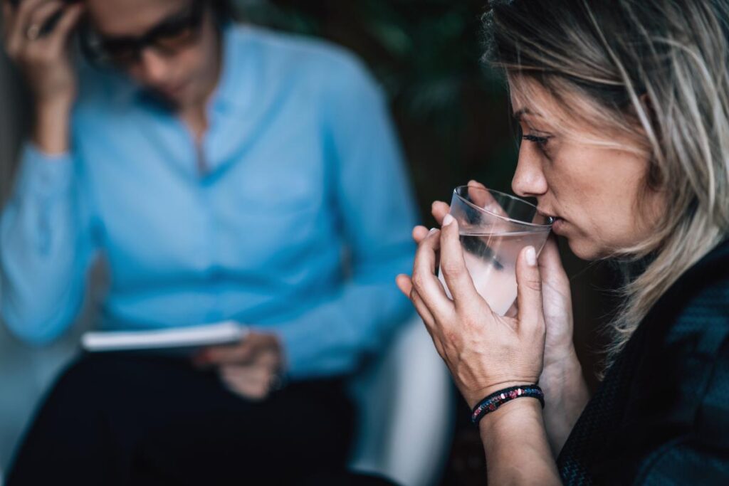 Woman drinks water while learning about the dangers of mixing alcohol and benzos