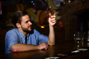 Man sits at bar, showing signs of alcohol use
