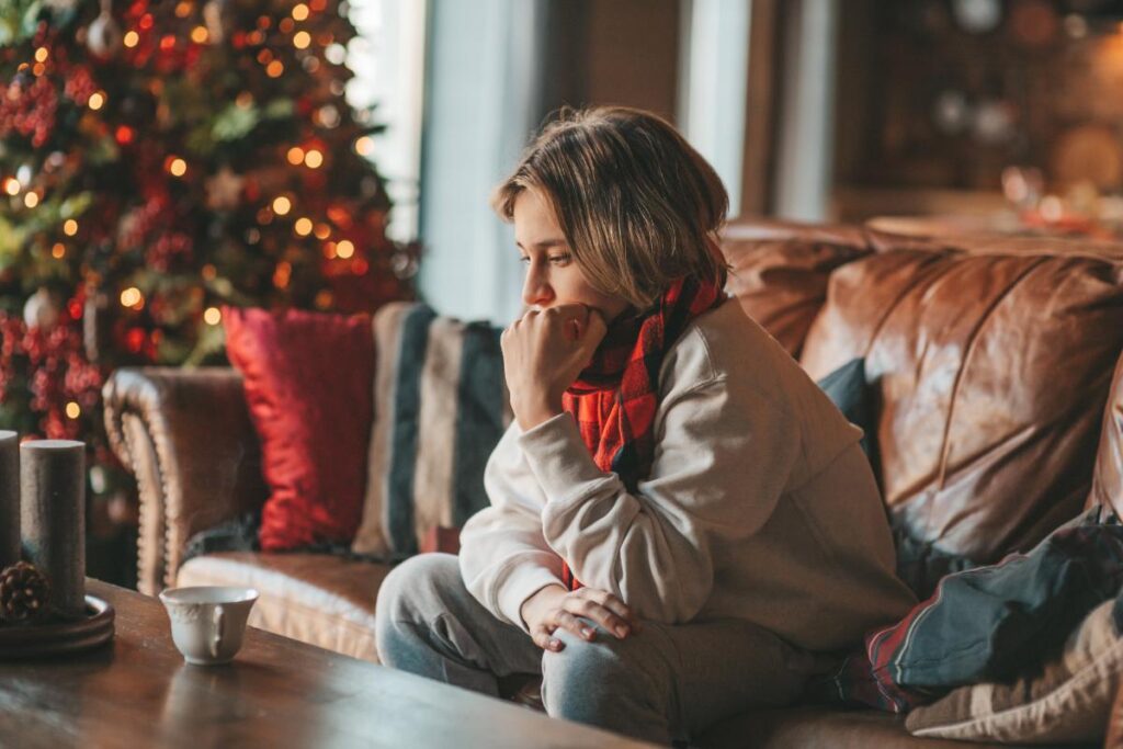 Woman sits on couch as she struggles for relapse triggers during the holidays