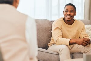 Man sits on couch and listens to therapist during transitional recovery program
